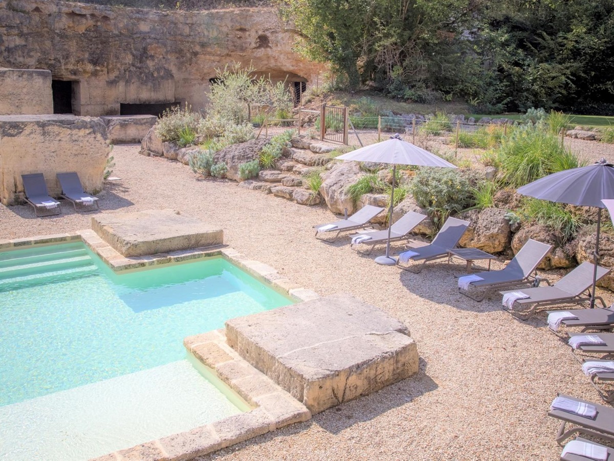Pool and gated pool area with sun loungers, umbrellas and plants at La Colline Bleue in South West France