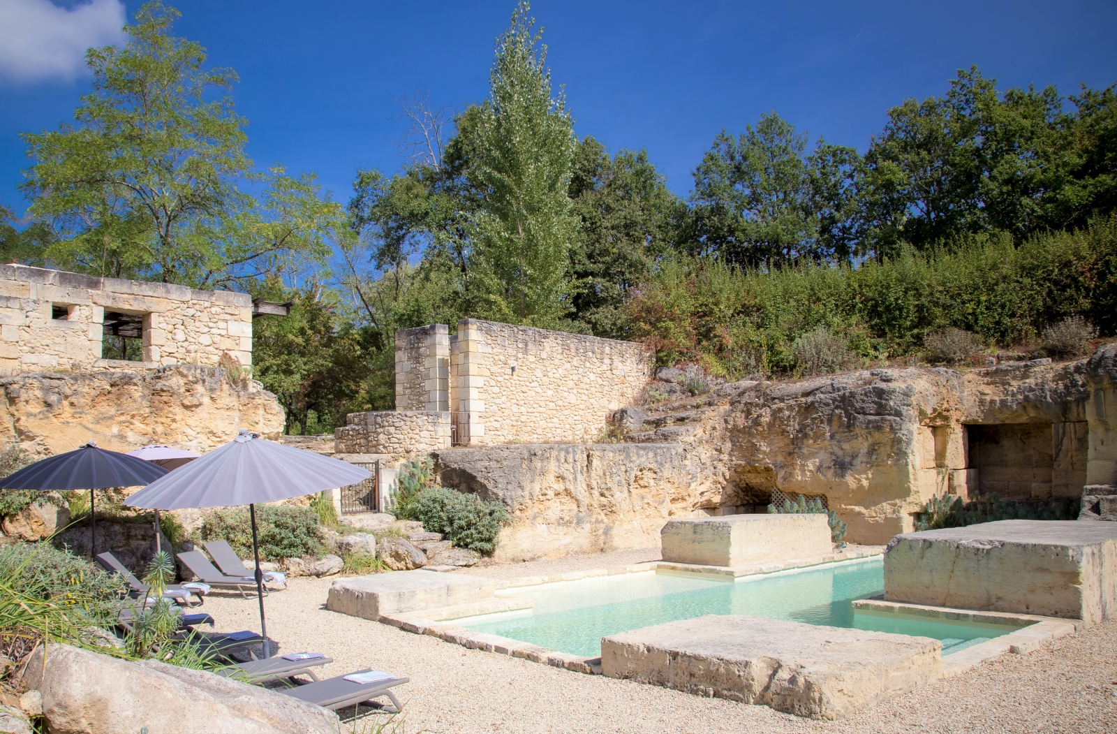 Pool and gated pool area with sun loungers, umbrellas and plants at La Colline Bleue in South West France