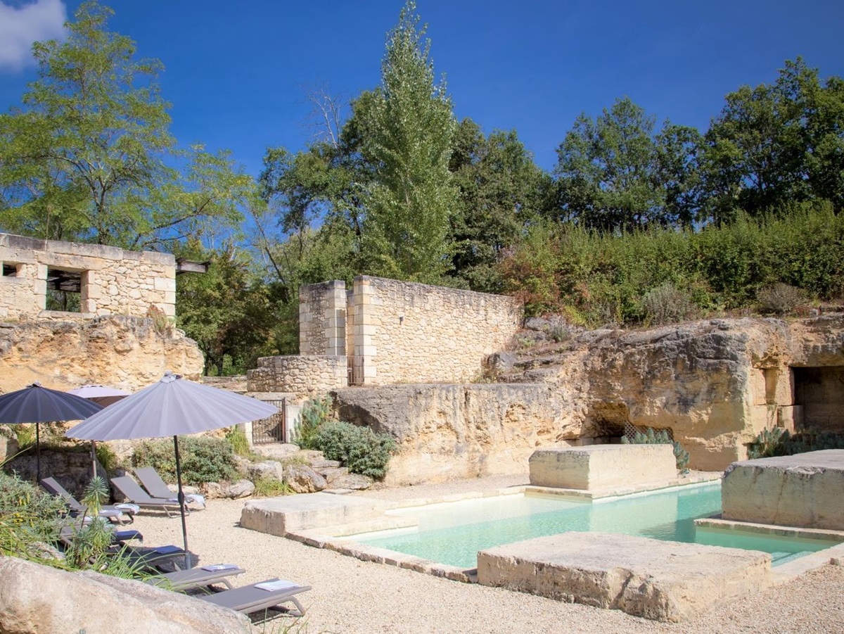 Pool and gated pool area with sun loungers, umbrellas and plants at La Colline Bleue in South West France