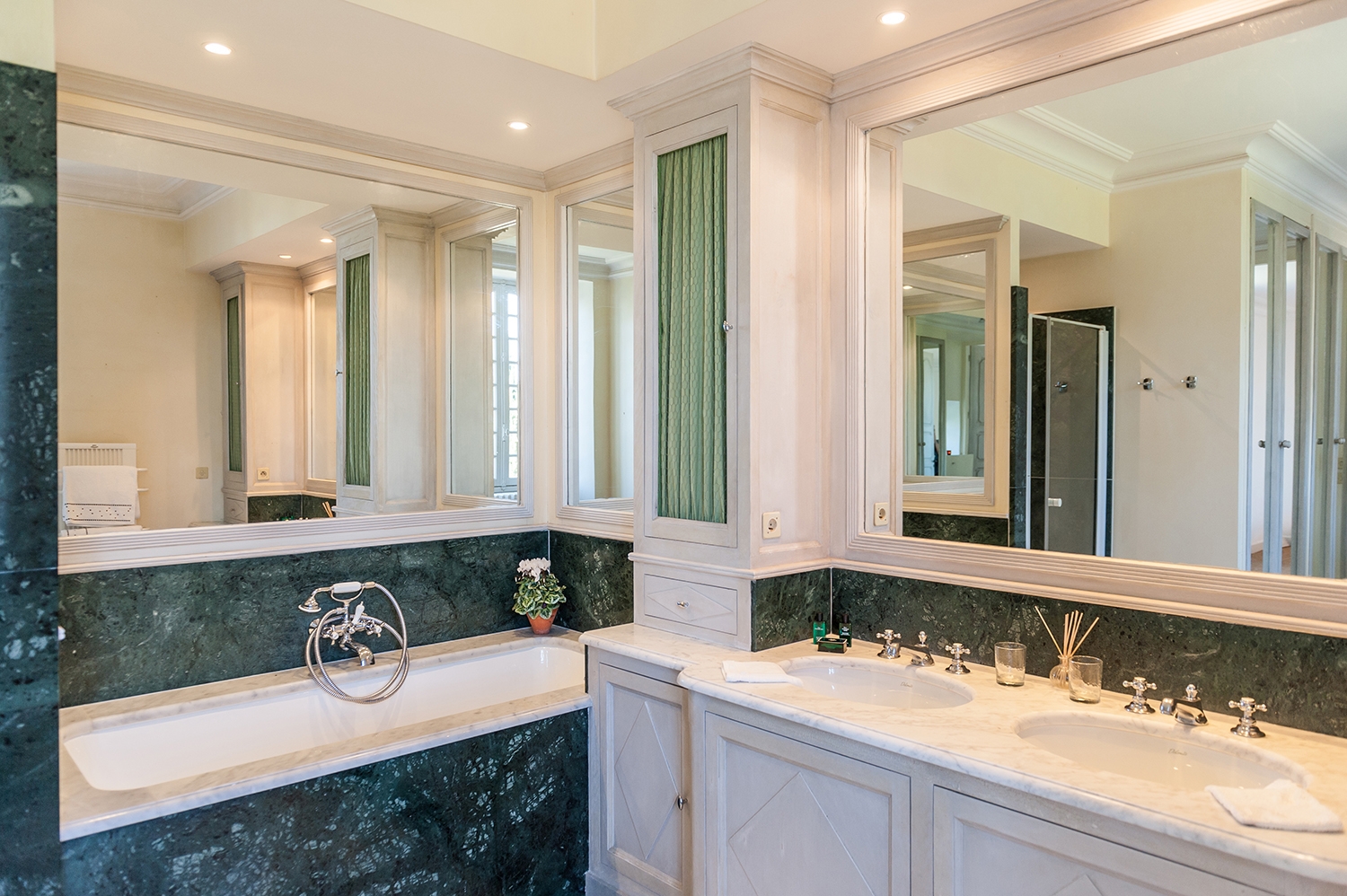 Bathroom with marble bath, double sinks, flower and large mirror at Maison de Cales in South West France