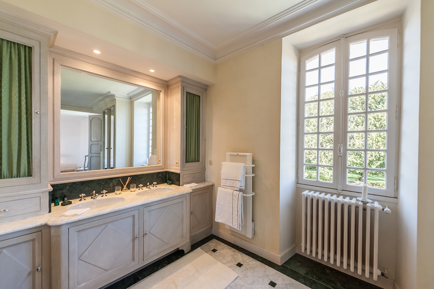 Bathroom with double sinks, large mirror, towel rail and window at Maison de Cales in South West France