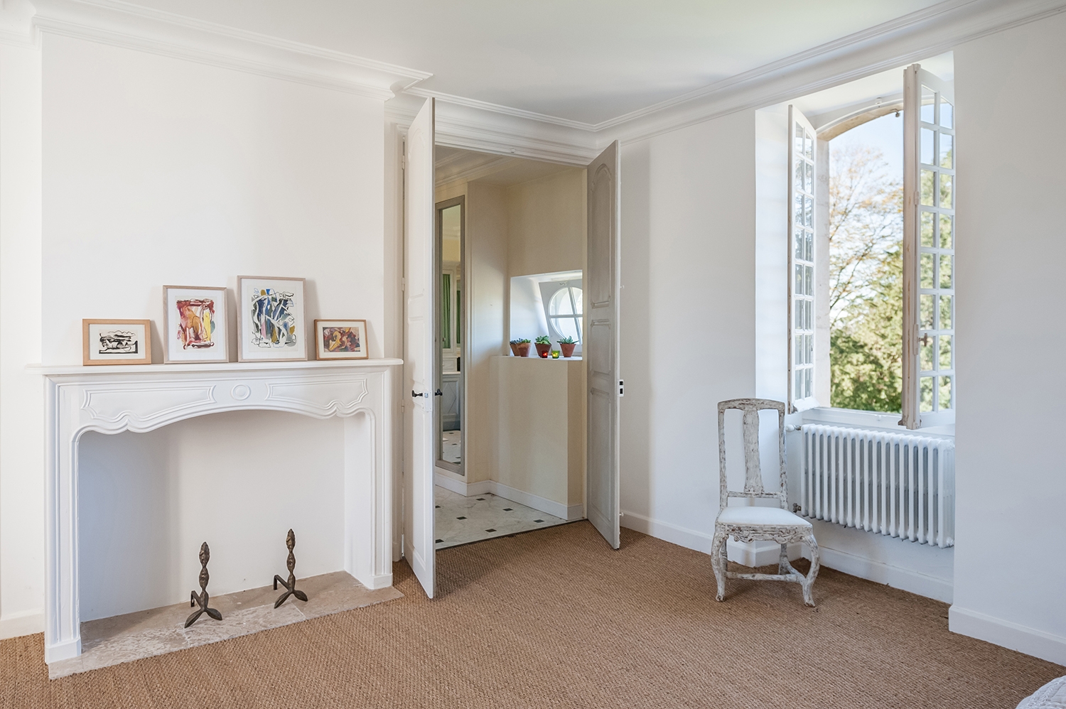 Bedroom with fireplace, picture frames, chair, window and ensuite bathroom at Maison de Cales in South West France