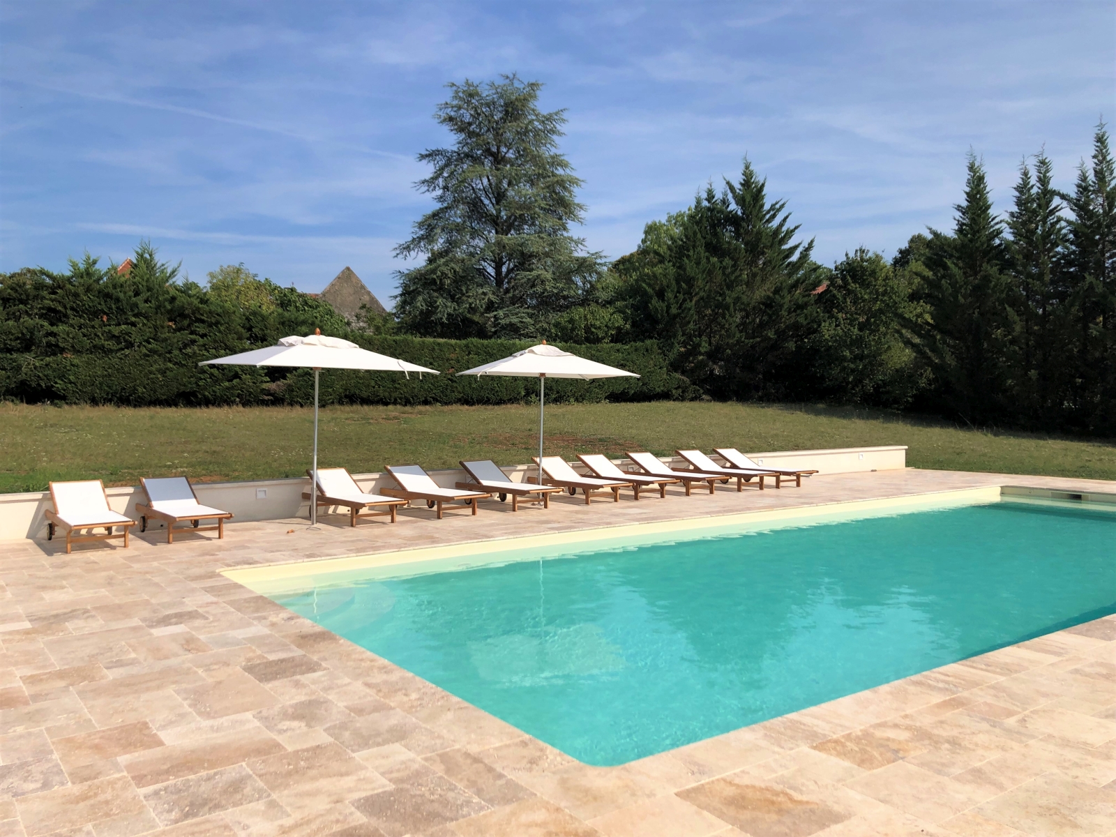 Pool and pool area with sun loungers and umbrellas at Maison de Cales in South West France