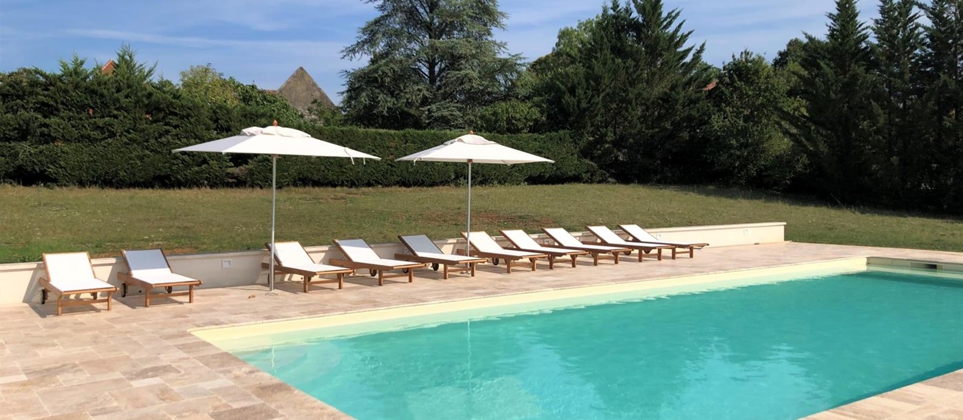 Pool and pool area with sun loungers and umbrellas at Maison de Cales in South West France