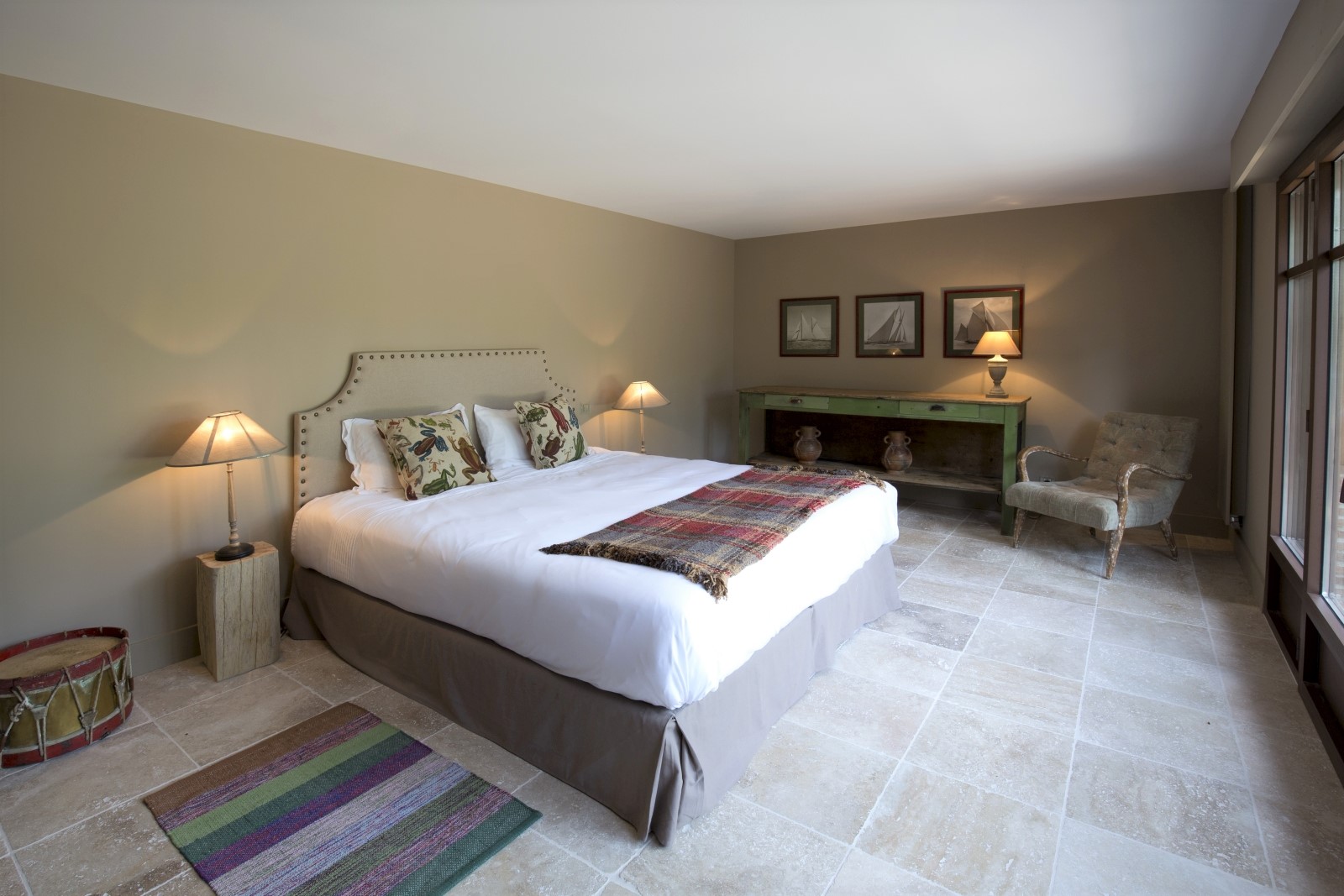 Bedroom with double bed, lamps, armchair, table and picture frames at Villa Carmen in South West France
