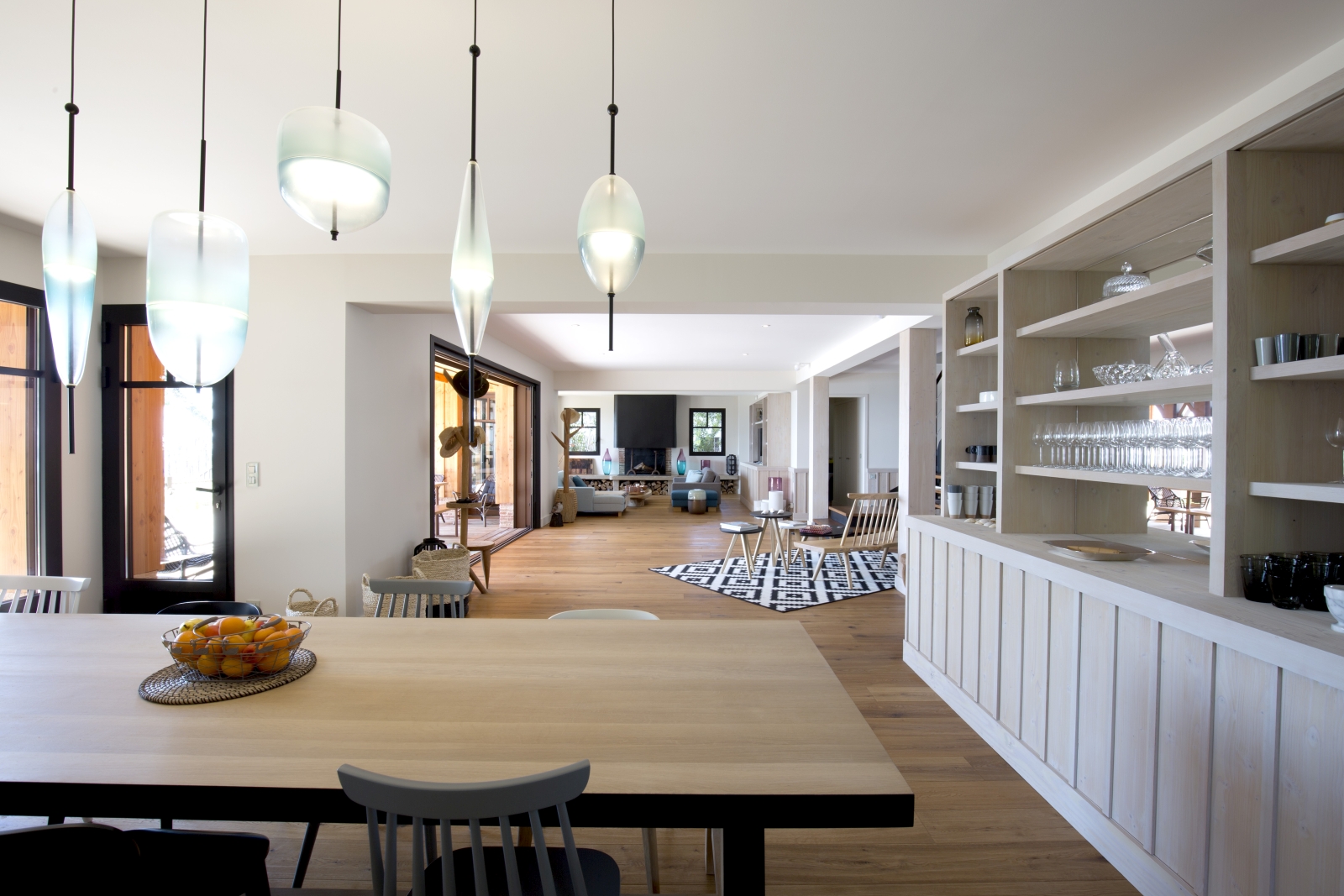 Dining area with table, chairs, fruit bowl, hanging lights and shelves at Villa Carmen in South West France