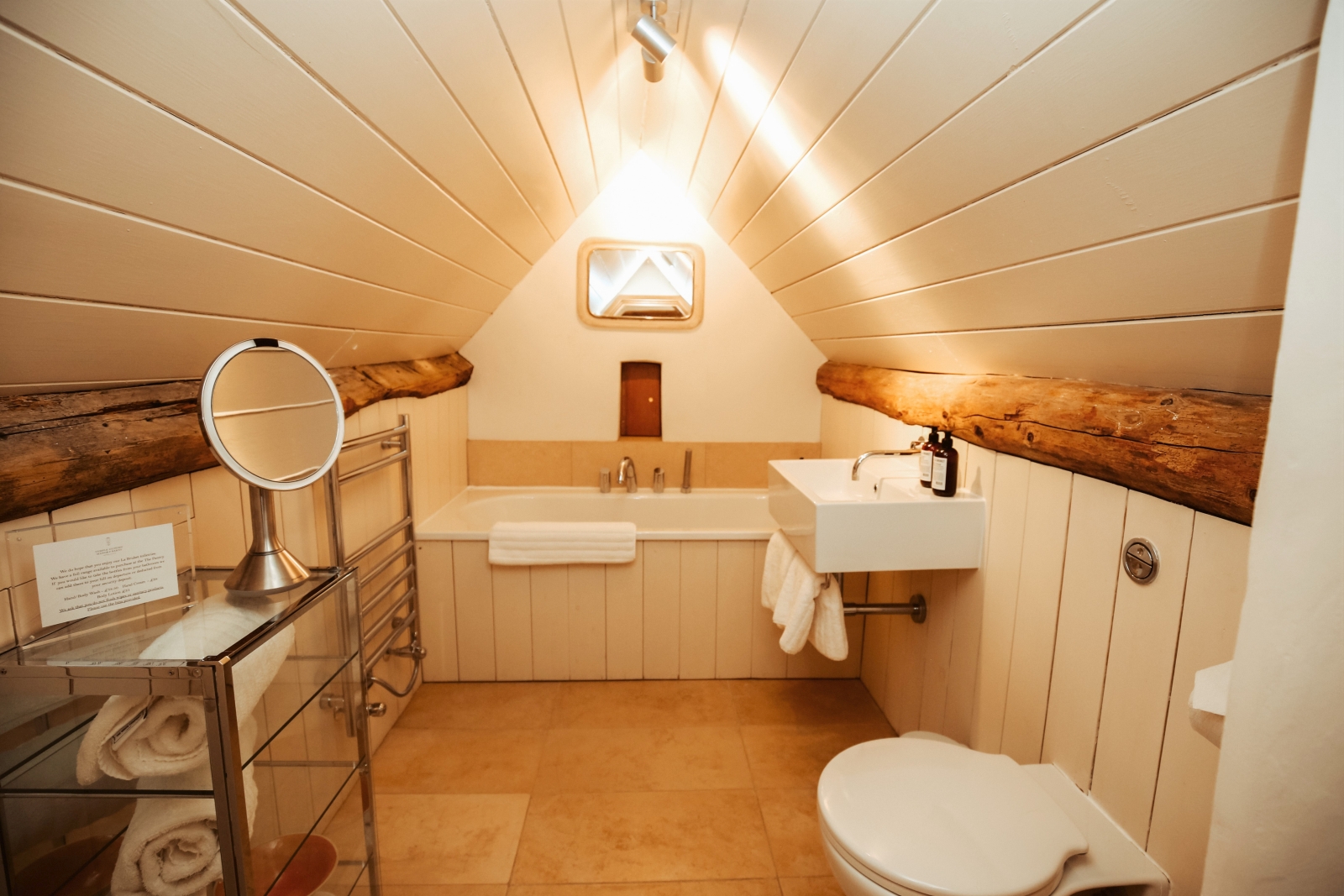Attic bathroom with toilet, sink, bath, mirror and cabinet at Temple Guiting Barn in the Cotswolds, England