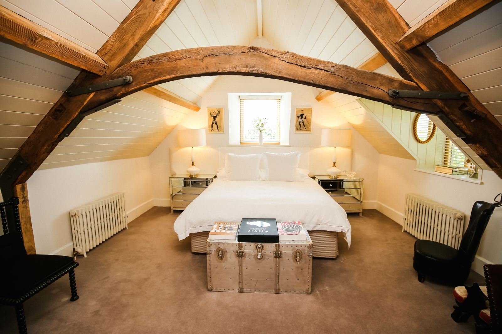 Bedroom with double bed, chest, bedside tables, lamps and chairs at Temple Guiting Barn in the Cotswolds, England