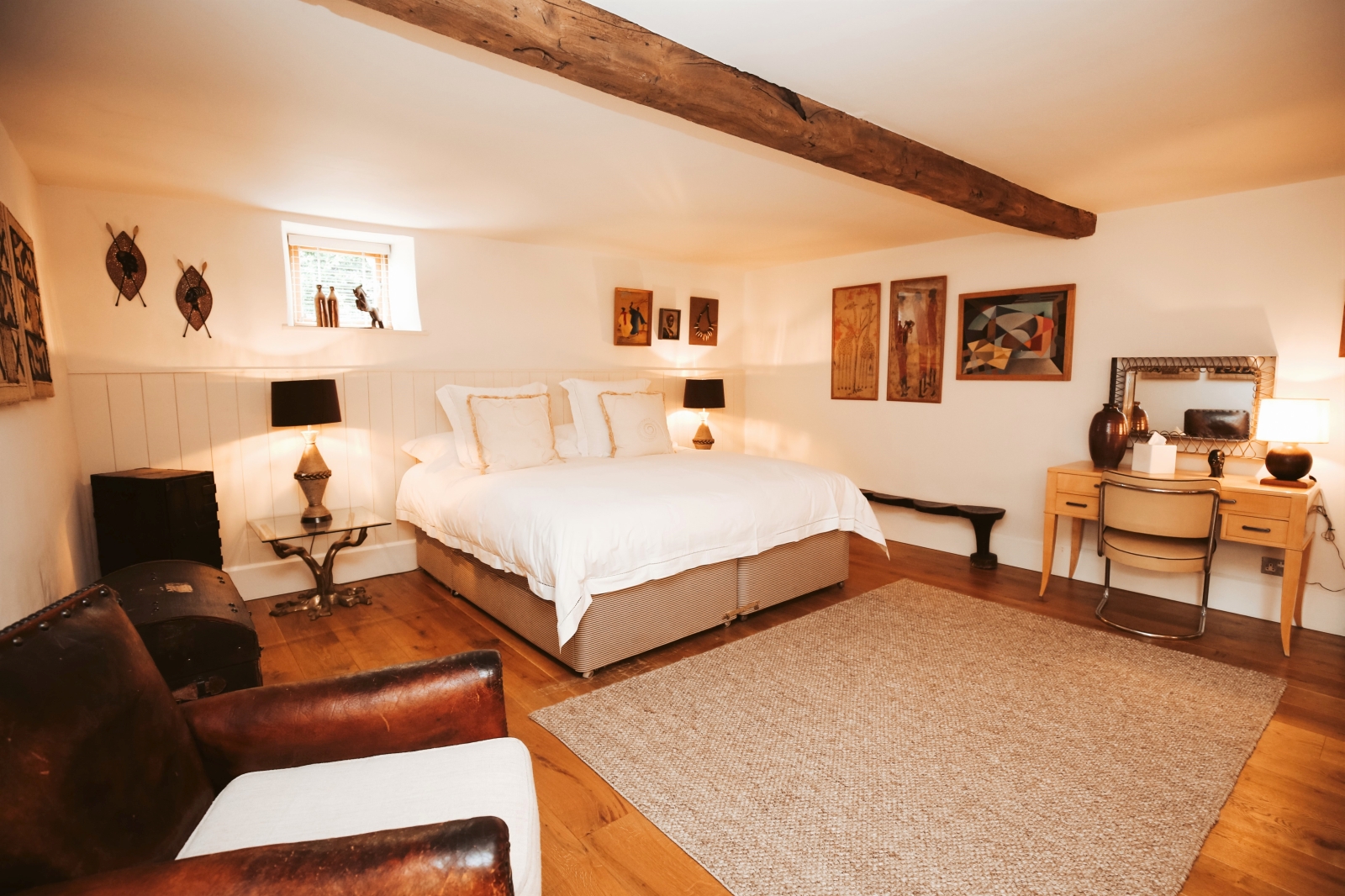Bedroom with double bed, bedside tables, lamps, armchair and dressing table at Temple Guiting Barn in the Cotswolds, England