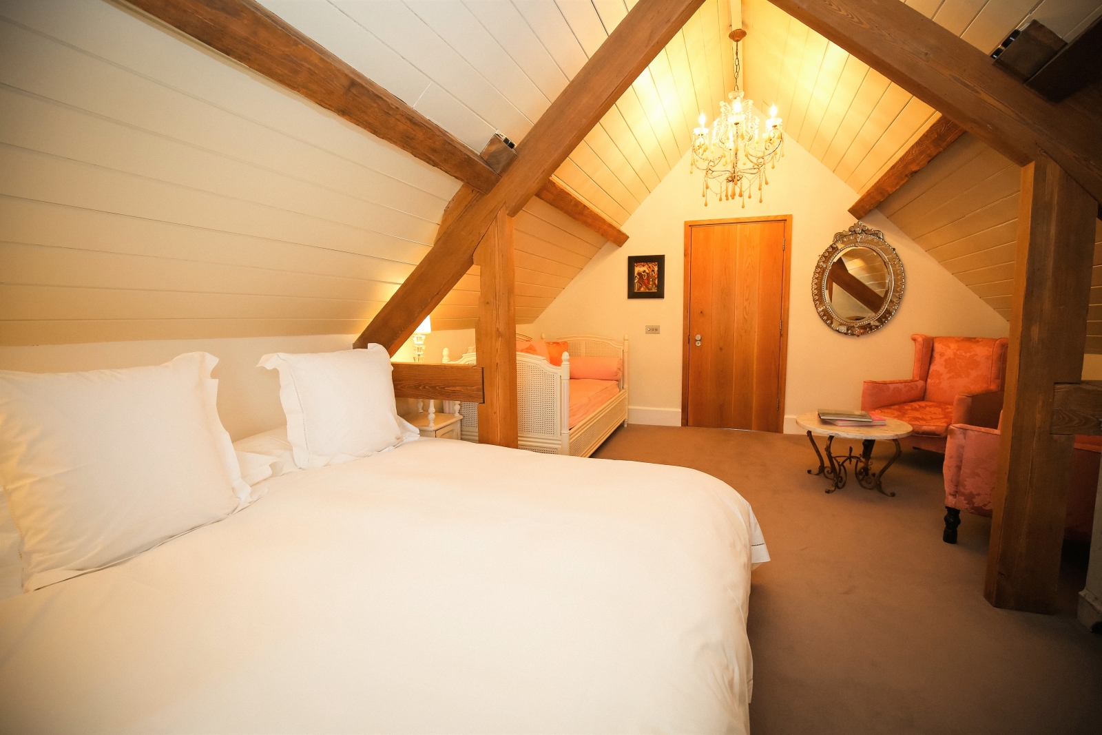 Bedroom with double bed, single bed, armchairs, table and chandelier at Temple Guiting Barn in the Cotswolds, England