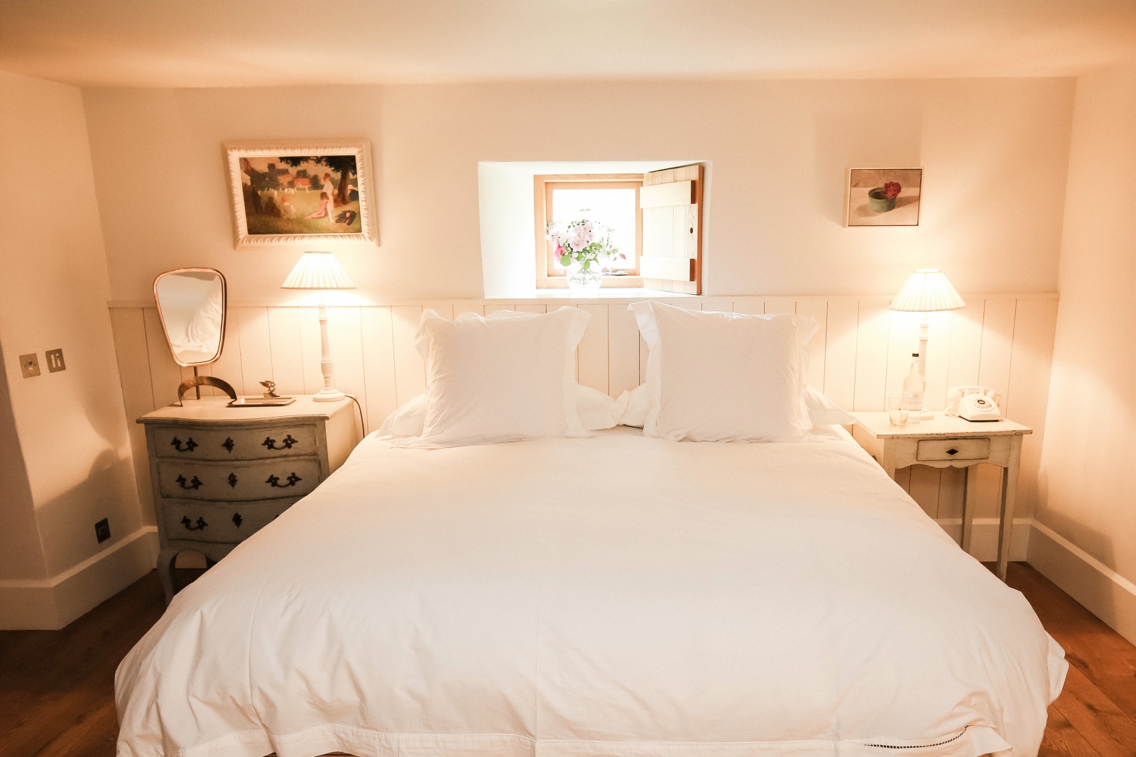Bedroom with double bed, bedside tables, lamps, mirror and pictures frames at Temple Guiting Barn in the Cotswolds, England