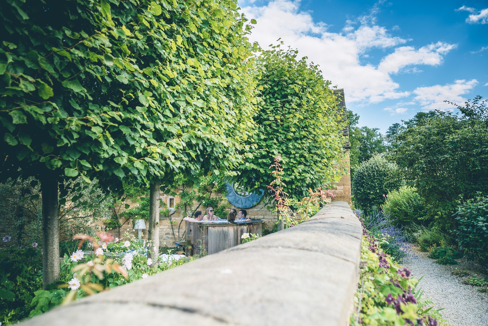Garden with trees, plants, flowers and hot tub at Temple Guiting Barn in the Cotswolds, England