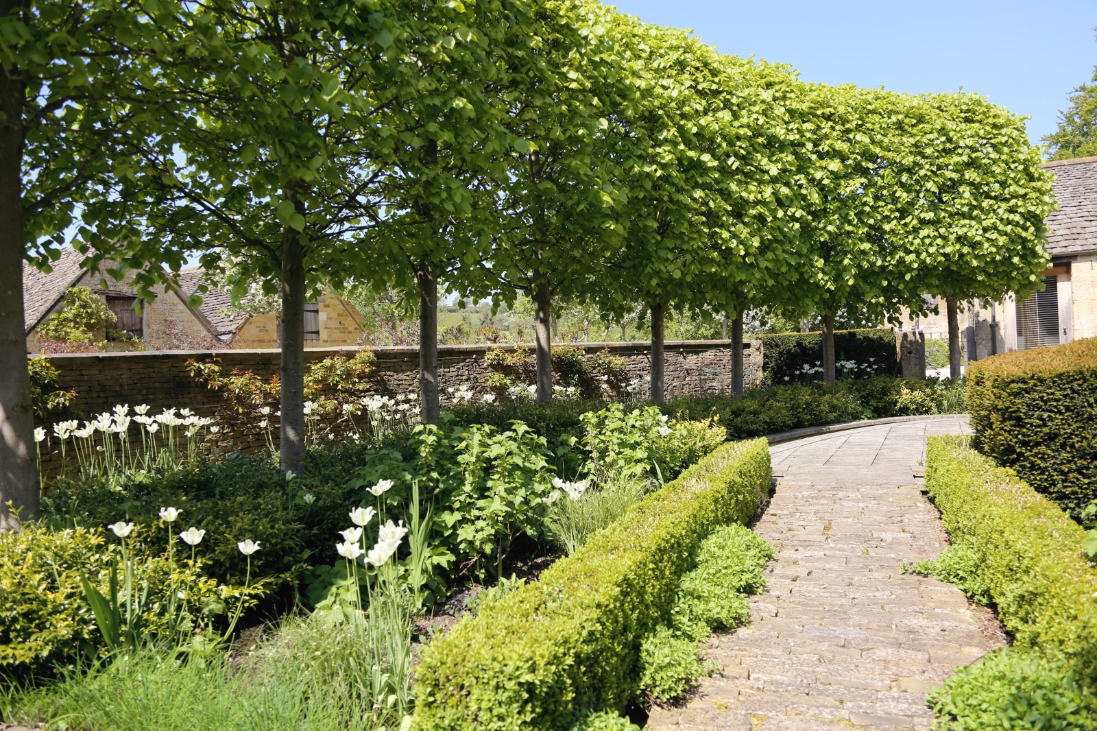 Garden with hedges, trees and flowers at Temple Guiting Barn in the Cotswolds, England