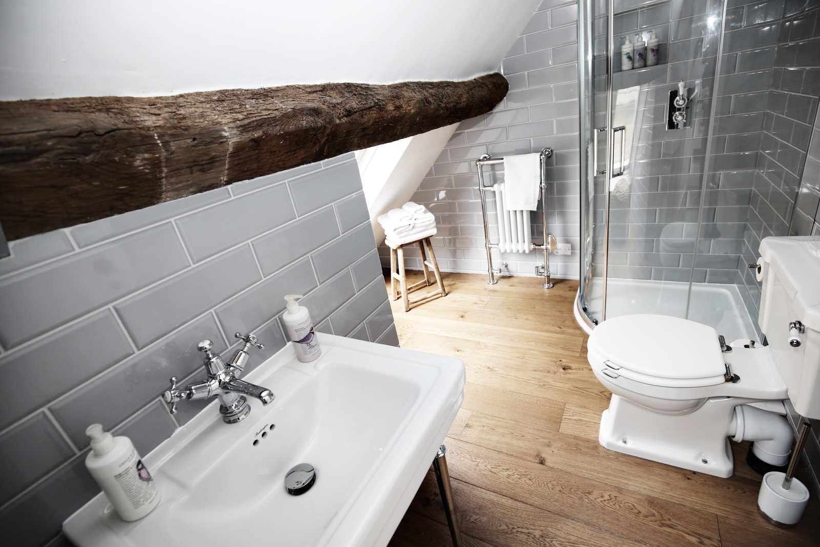 Bathroom with sink, toilet, shower, towel rail and stool at The Estate at Temple Guiting in the Cotswolds, England