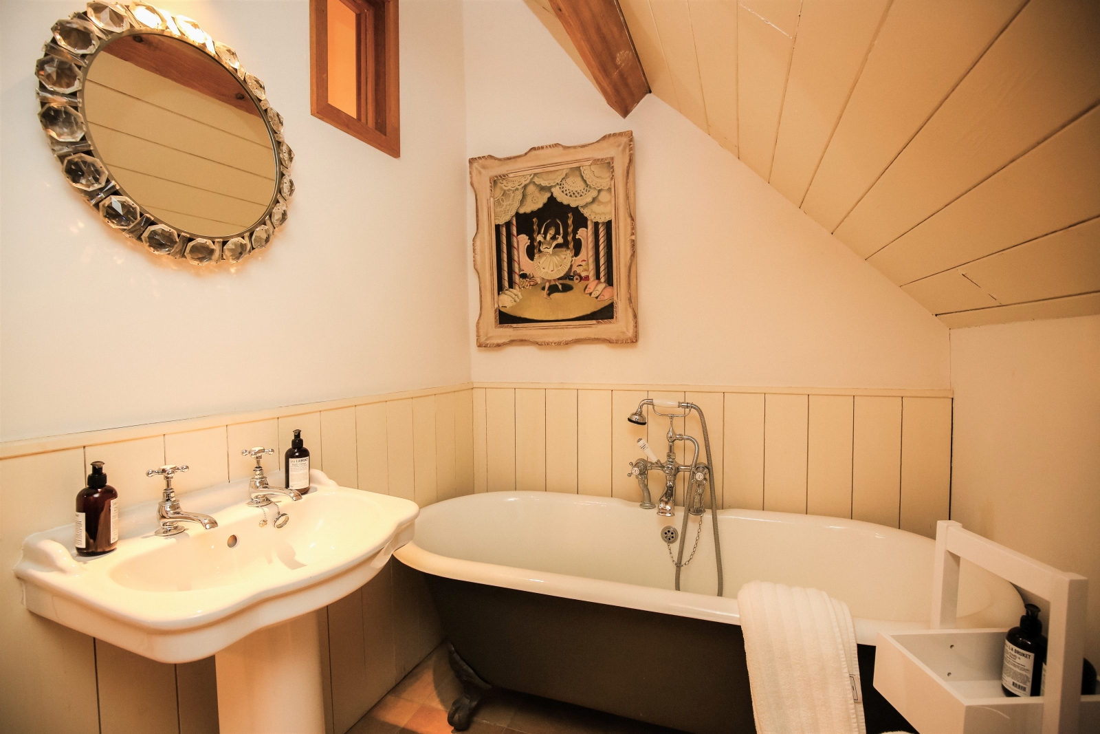 Bathroom with bath, sink, mirror, picture frame and caddy at The Estate at Temple Guiting in the Cotswolds, England