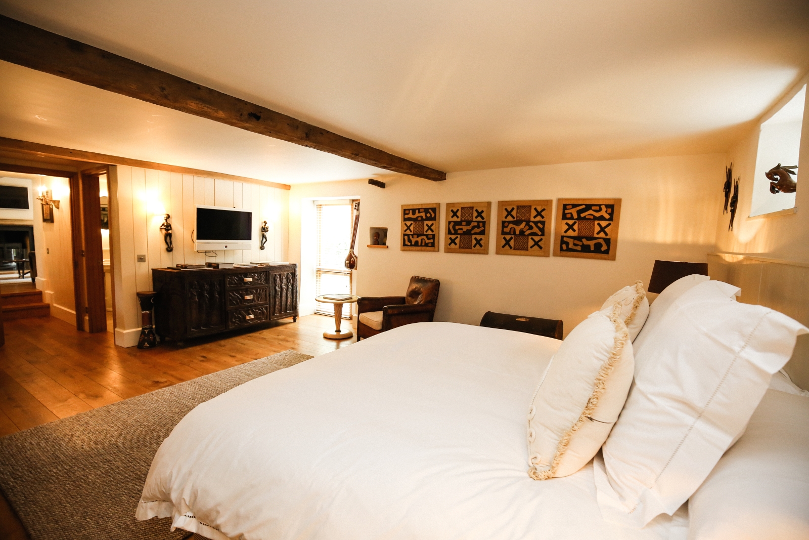 Bedroom with double bed, armchair, table, cabinet, TV and artwork at The Estate at Temple Guiting in the Cotswolds, England