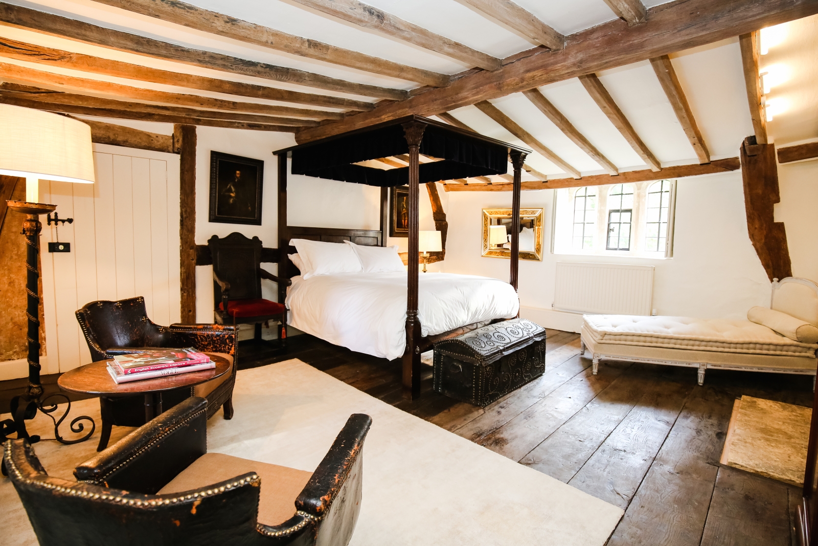 Bedroom with armchairs, four poster double bed & chaise longue at The Estate at Temple Guiting in the Cotswolds, England
