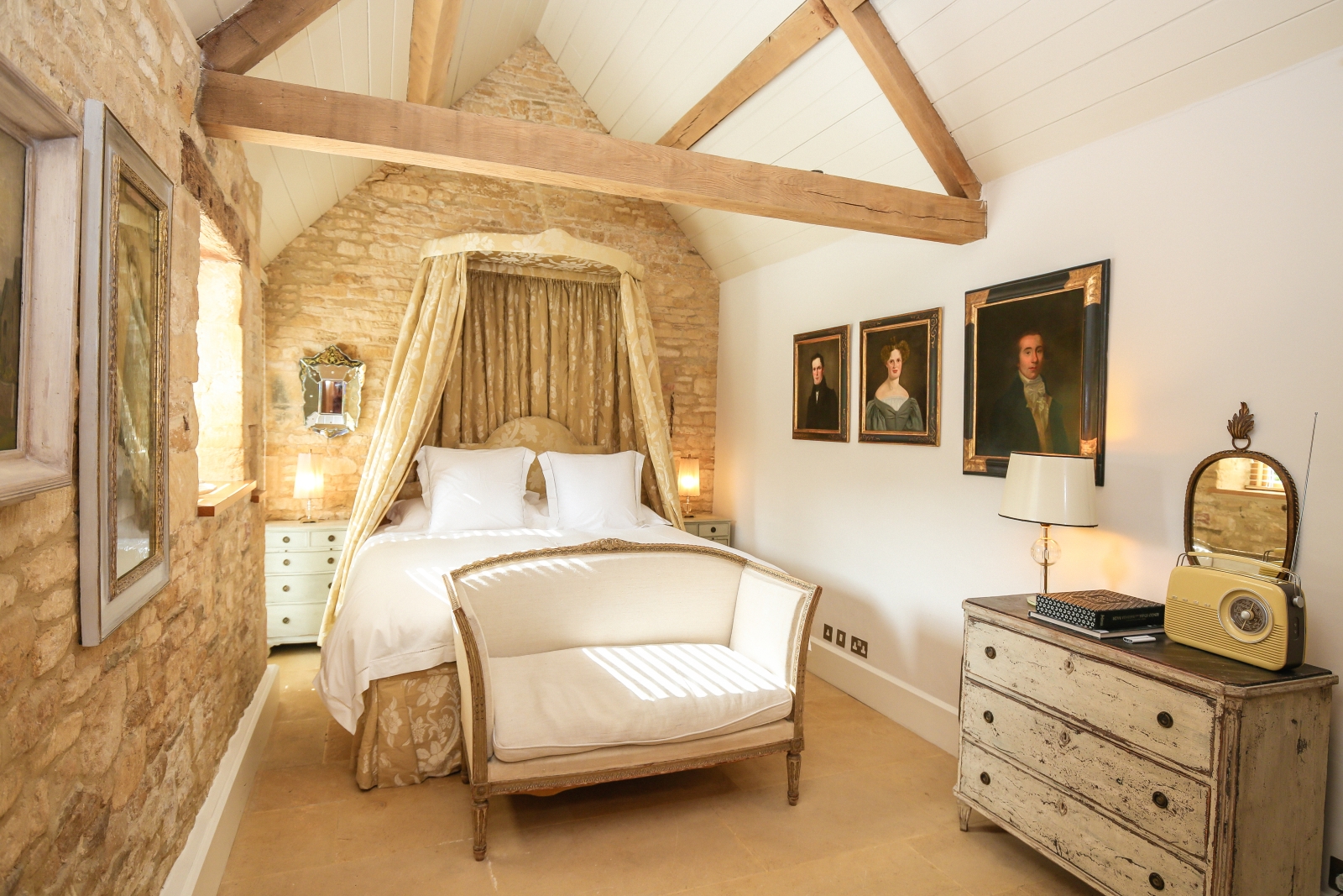 Bedroom with double bed, comfy chair, chest of drawers & paintings at The Estate at Temple Guiting in the Cotswolds, England