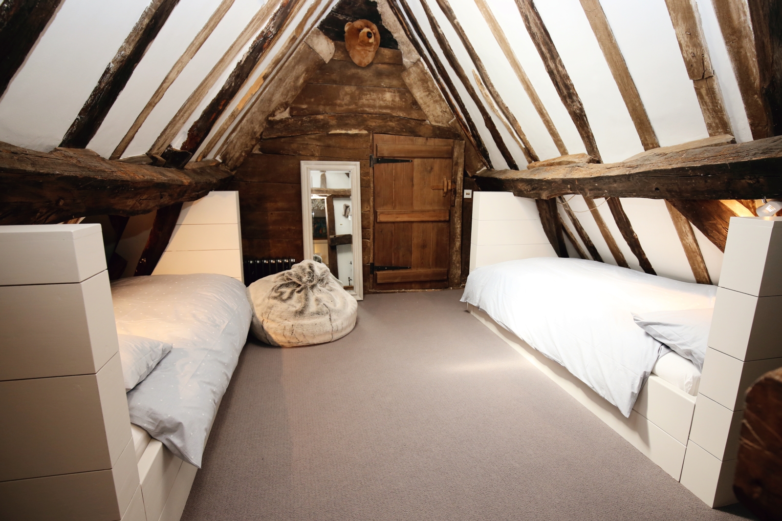 Bedroom with twin beds, beanbag, long mirror and ceiling beams at The Estate at Temple Guiting in the Cotswolds, England