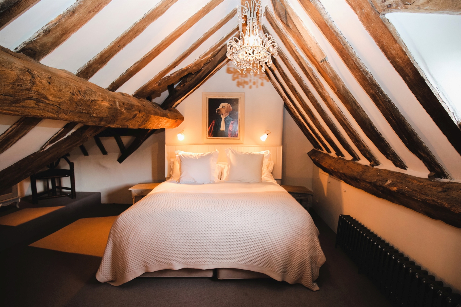 Bedroom with double bed, chandelier and ceiling beams at The Estate at Temple Guiting in the Cotswolds, England
