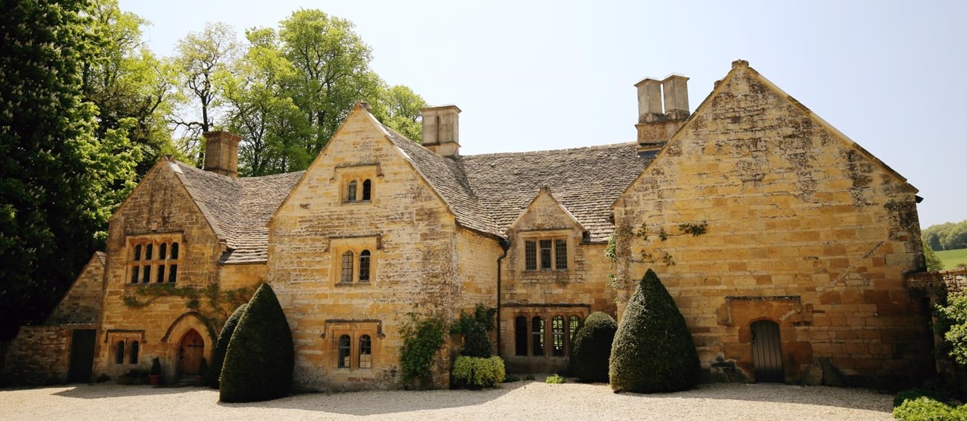 Cotswold stone front of villa with hedges and plants at The Estate at Temple Guiting in the Cotswolds, England
