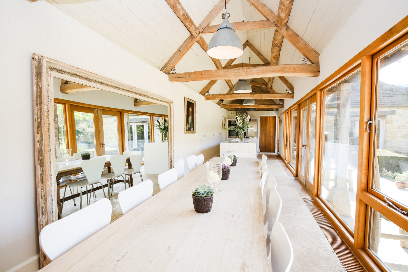 Dining area in kitchen with table, chairs, flowers and candles at The Estate at Temple Guiting in the Cotswolds, England