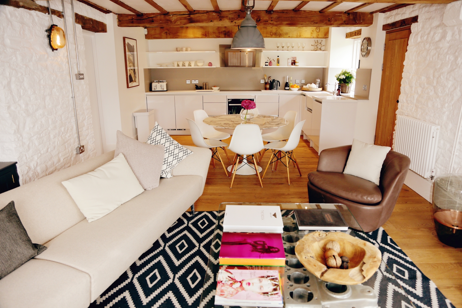 Living room and kitchen with sofa, armchair, tables & chairs at The Estate at Temple Guiting in the Cotswolds, England