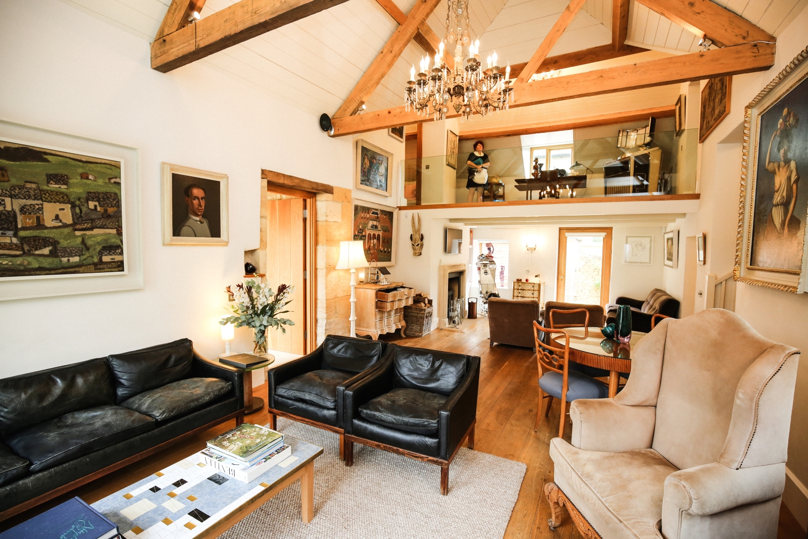 Living room with armchairs, sofas, table, chairs, lamps & paintings at The Estate at Temple Guiting in the Cotswolds, England