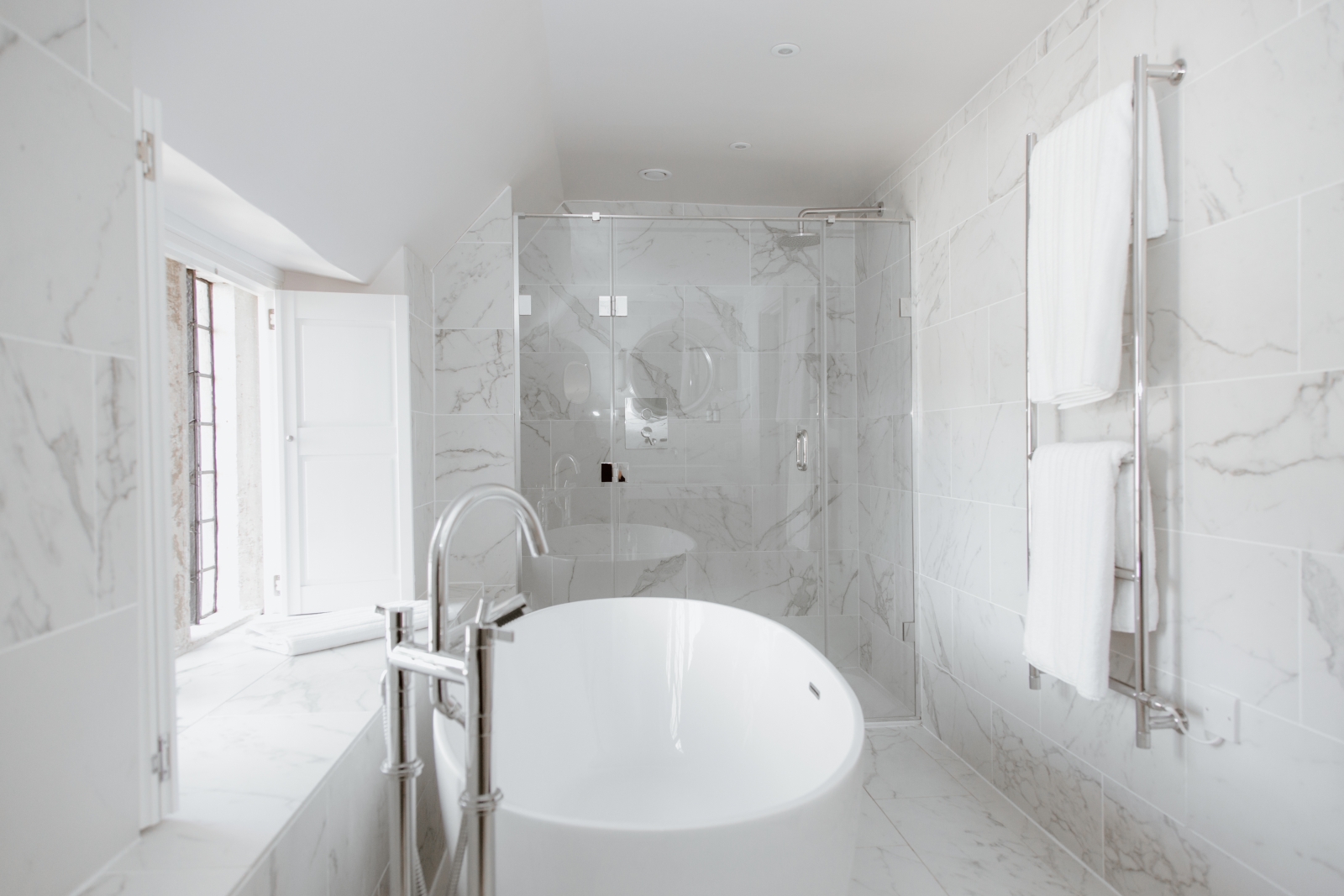All-marble bathroom with freestanding bathtub at English luxury villa Temple Guiting Manor