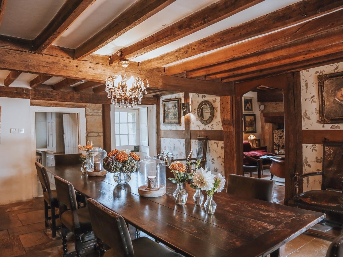 Extensive rustic dining room with exposed wooden beams at Temple Guiting Manor, Cotswolds, England