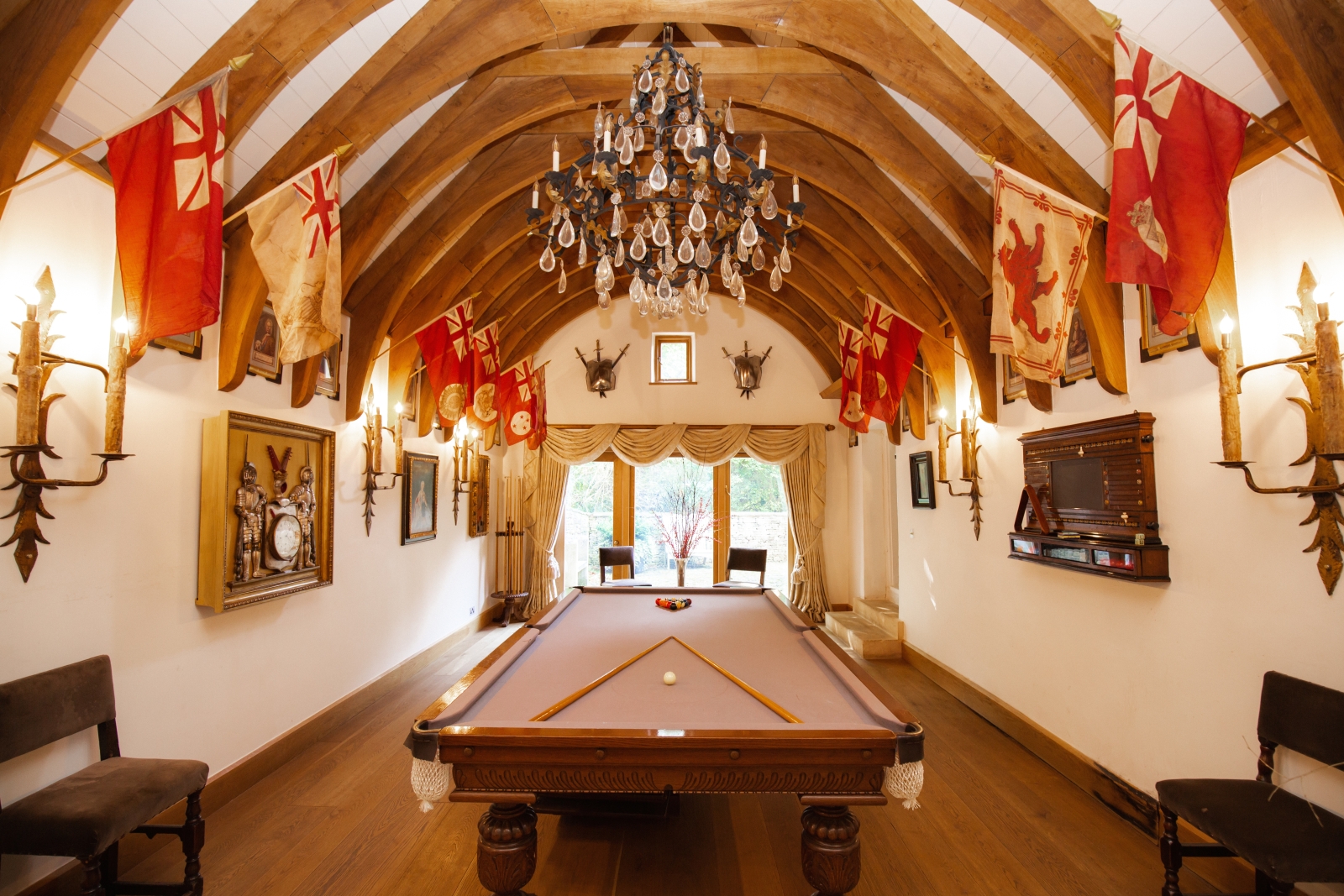 Pool table in a grande room with exposed wooden beams and decorated with flags at Temple Guiting Manor in the Cotswolds, United Kingdom