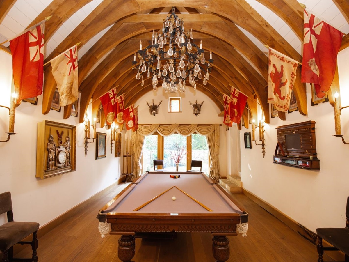 Pool table in a grande room with exposed wooden beams and decorated with flags at Temple Guiting Manor in the Cotswolds, United Kingdom