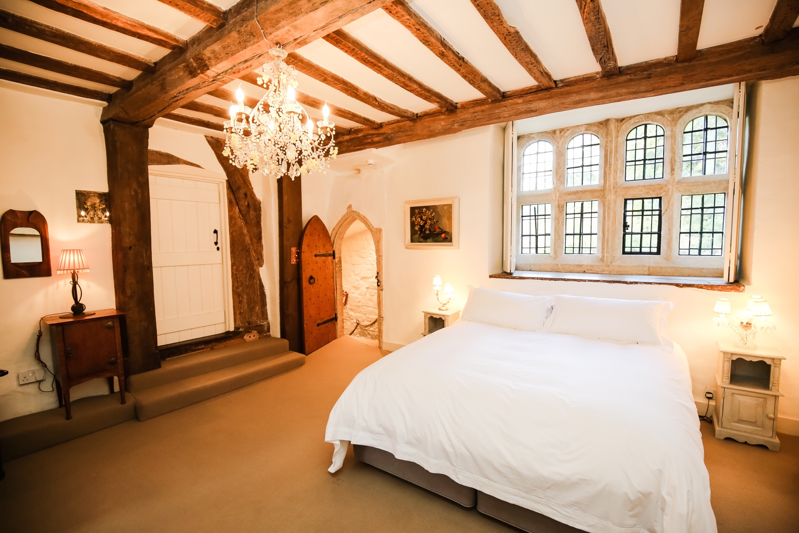 Bedroom with double bed, bedside tables, lamps and chandelier at Temple Guiting Manor in the Cotswolds, England