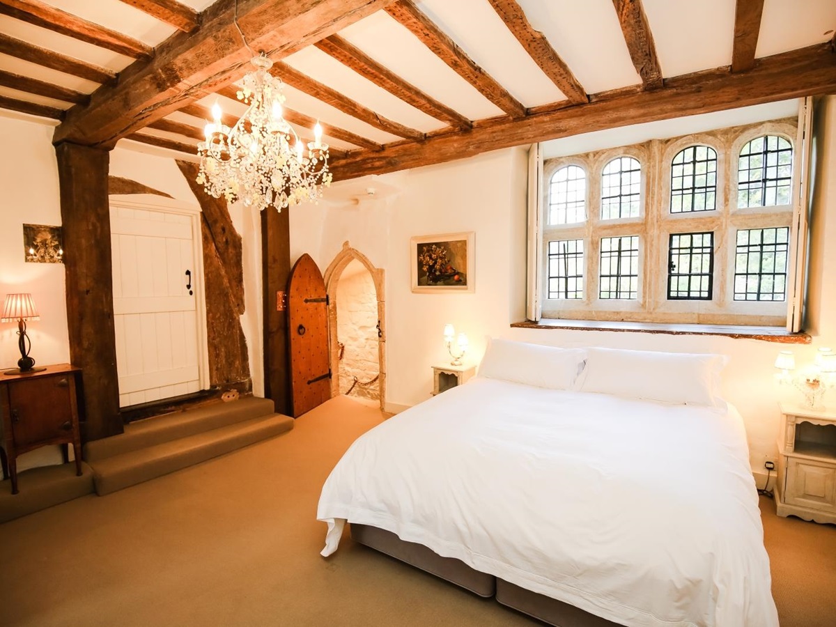 Bedroom with double bed, bedside tables, lamps and chandelier at Temple Guiting Manor in the Cotswolds, England