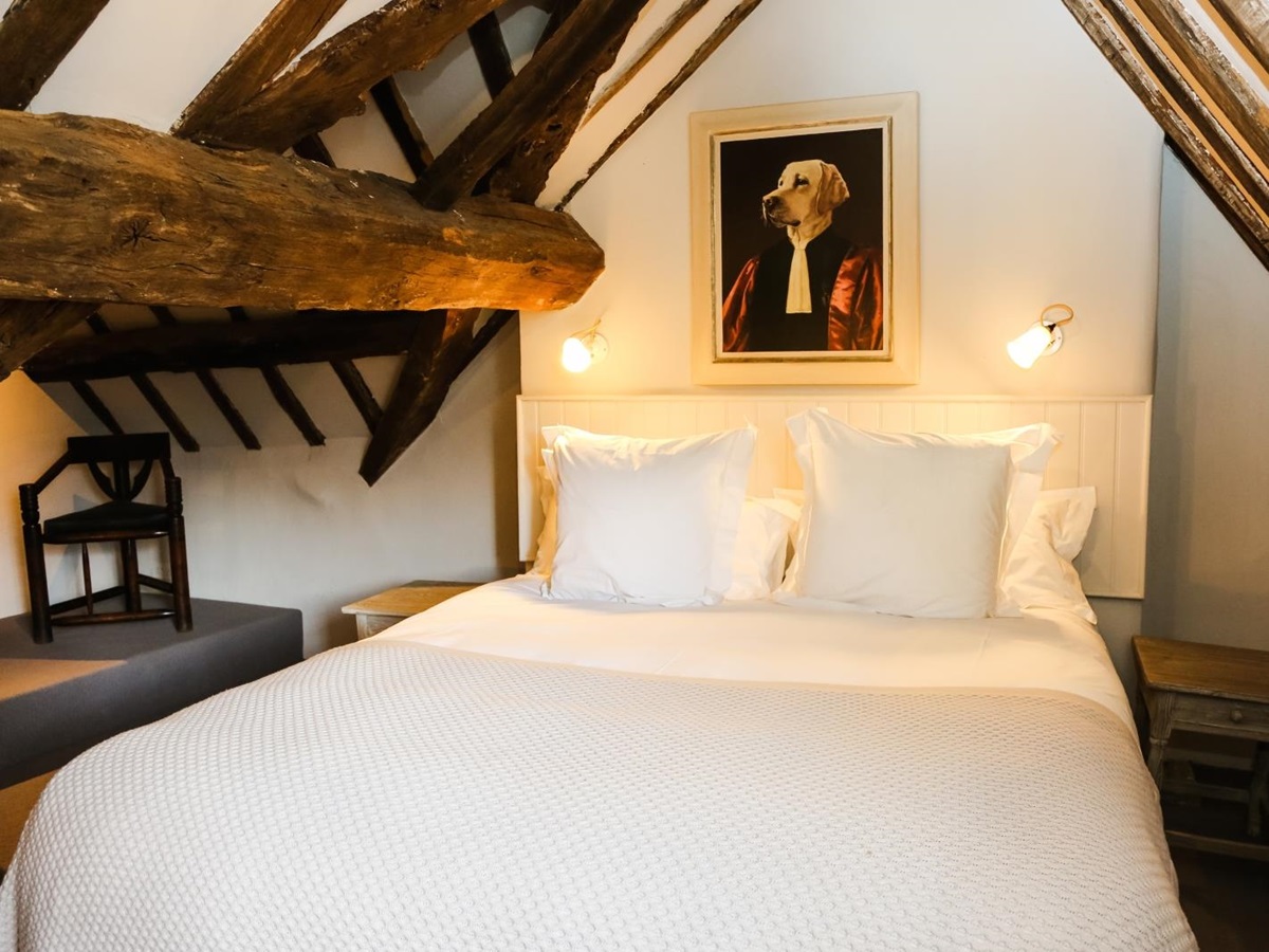 Bedroom with double bed, dog portrait and chair at Temple Guiting Manor in the Cotswolds, England