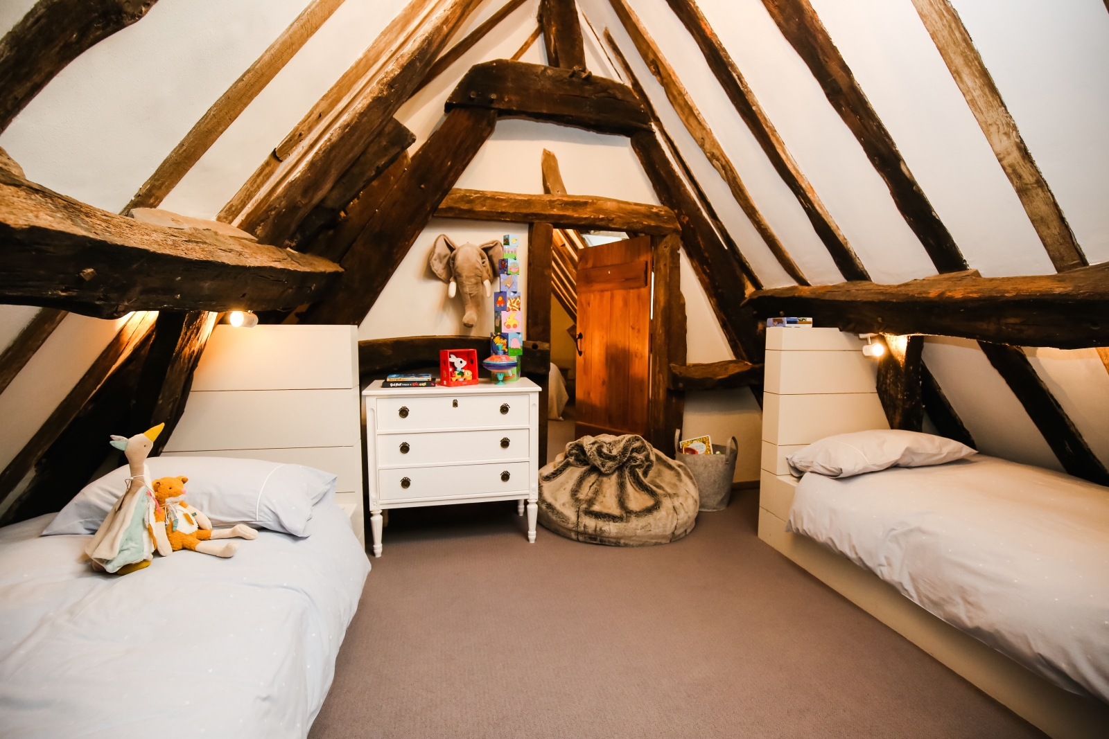 Bedroom with twin beds, children’s toys, chest of drawers and beanbag at Temple Guiting Manor in the Cotswolds, England