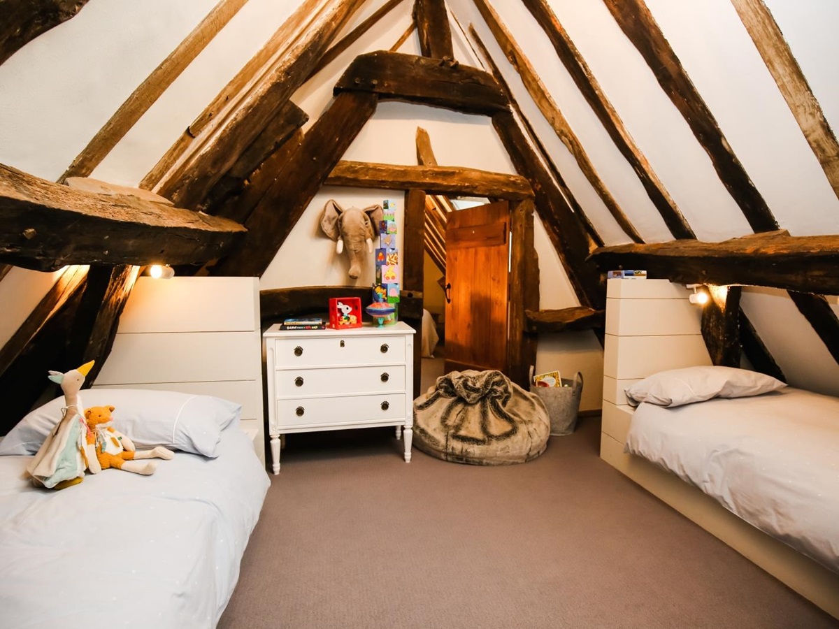 Bedroom with twin beds, children’s toys, chest of drawers and beanbag at Temple Guiting Manor in the Cotswolds, England