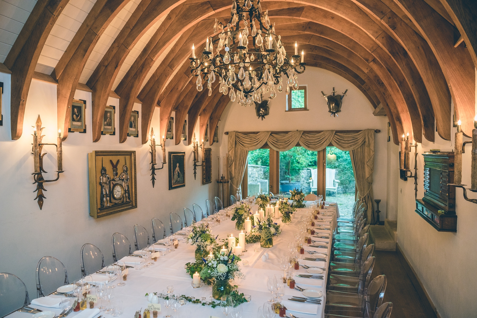 Dining room with set long table, chairs, paintings and chandelier at Temple Guiting Manor in the Cotswolds, England