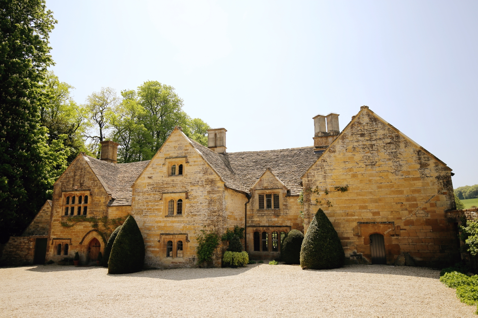Cotswold stone front of house with hedges and plants at Temple Guiting Manor in the Cotswolds, England