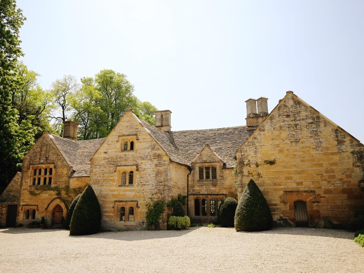 Cotswold stone front of house with hedges and plants at Temple Guiting Manor in the Cotswolds, England