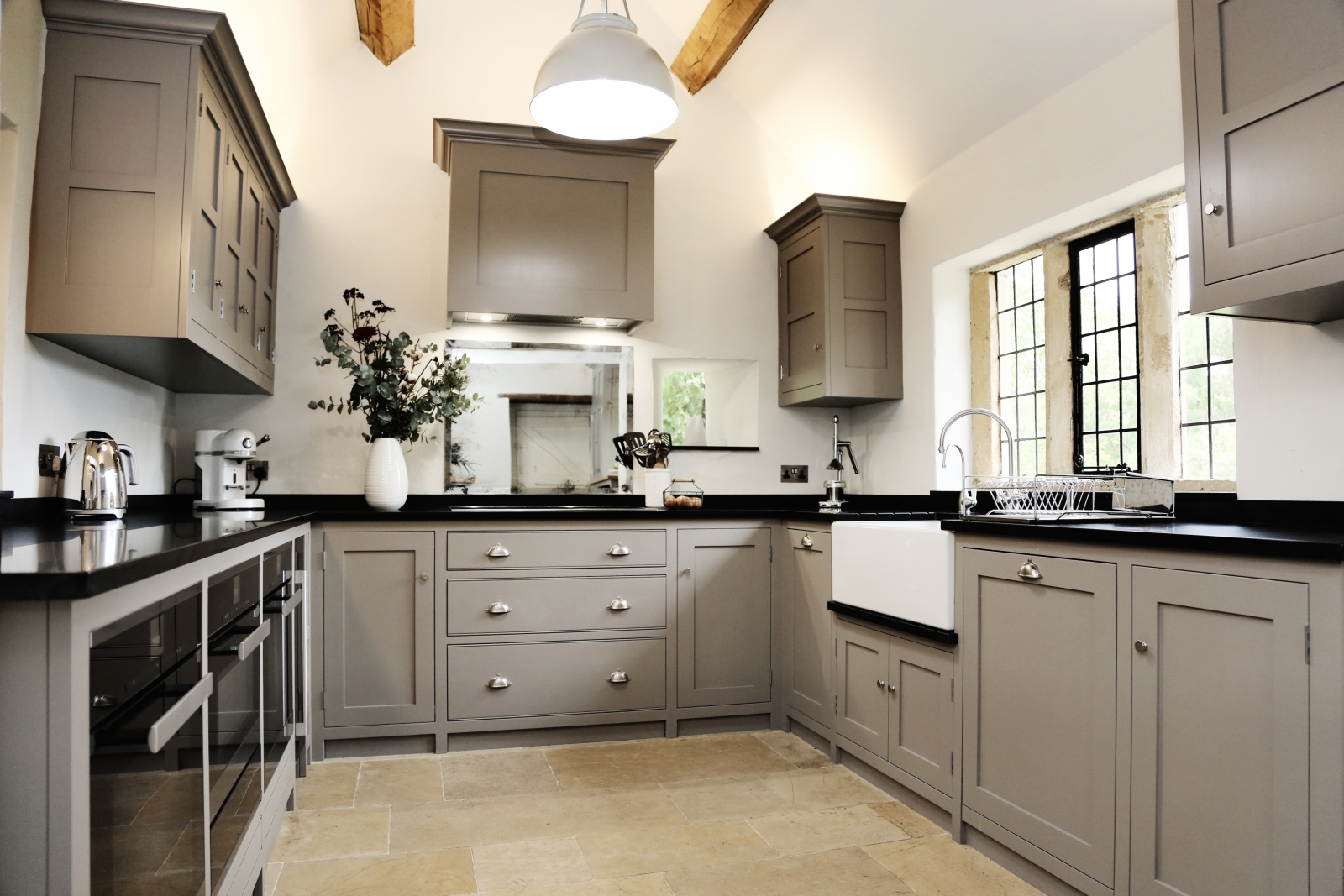 Kitchen with cupboards, appliances, sink, flowers and light at Temple Guiting Manor in the Cotswolds, England