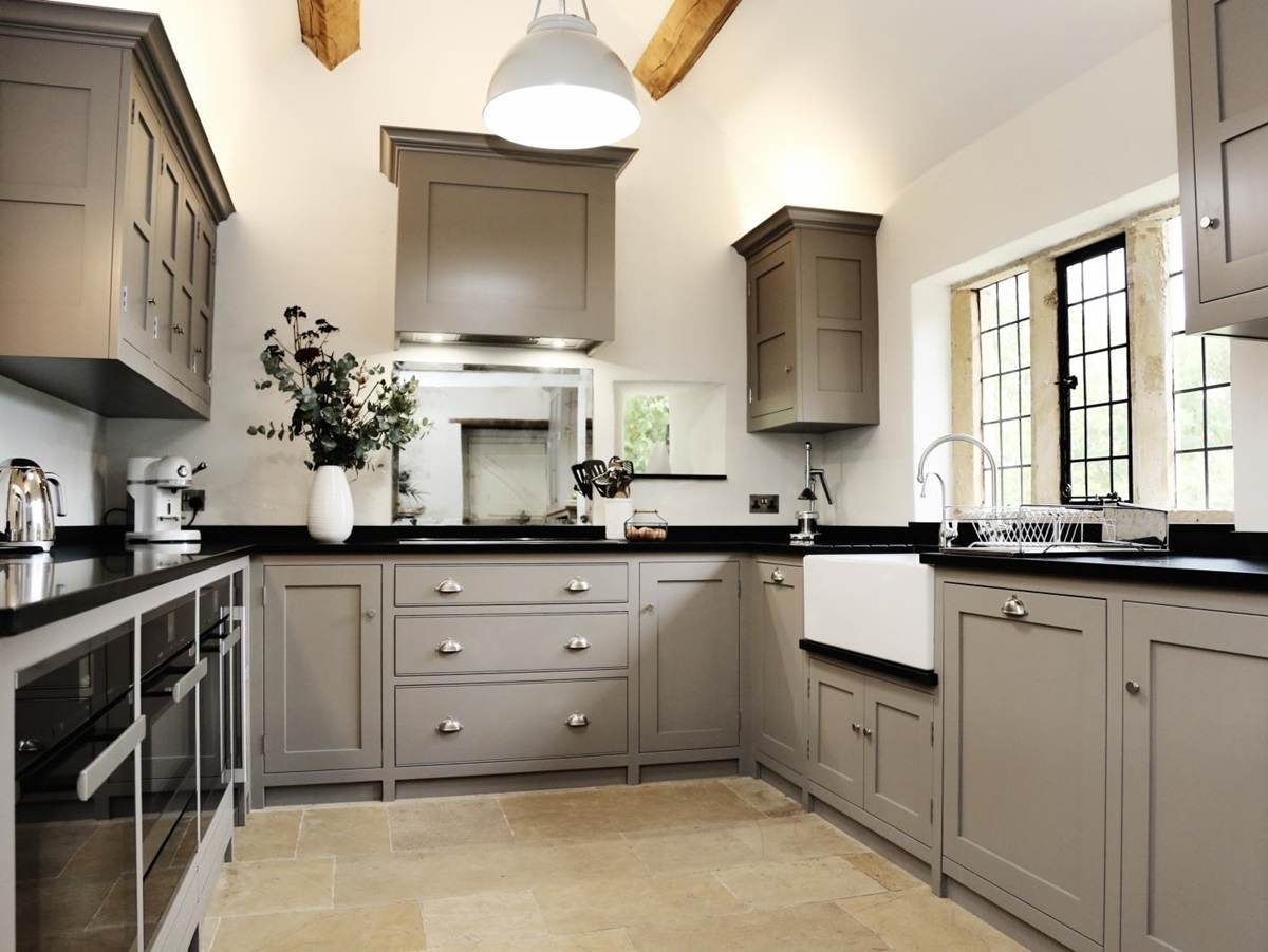 Kitchen with cupboards, appliances, sink, flowers and light at Temple Guiting Manor in the Cotswolds, England