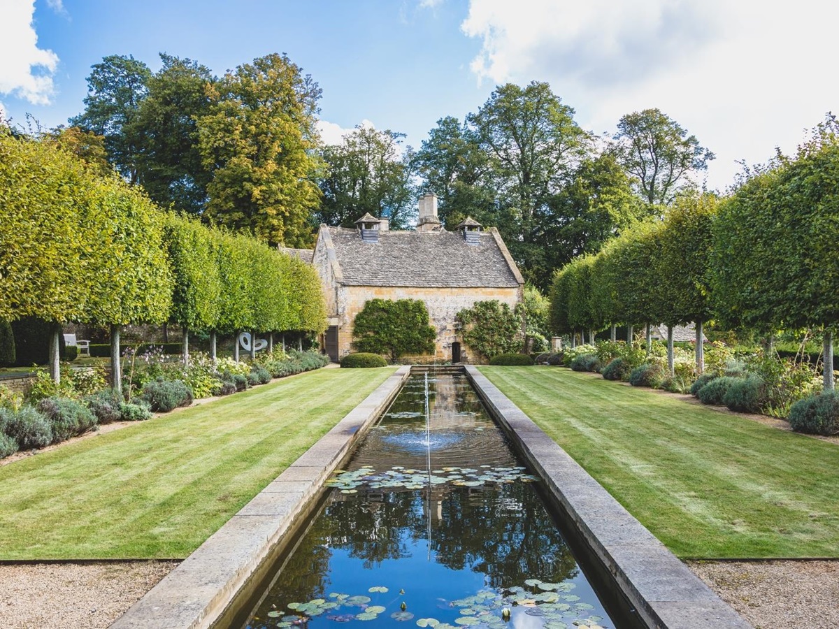 Water feature lined with trees leading to luxury villa Temple Guiting Manor in the Cotswolds