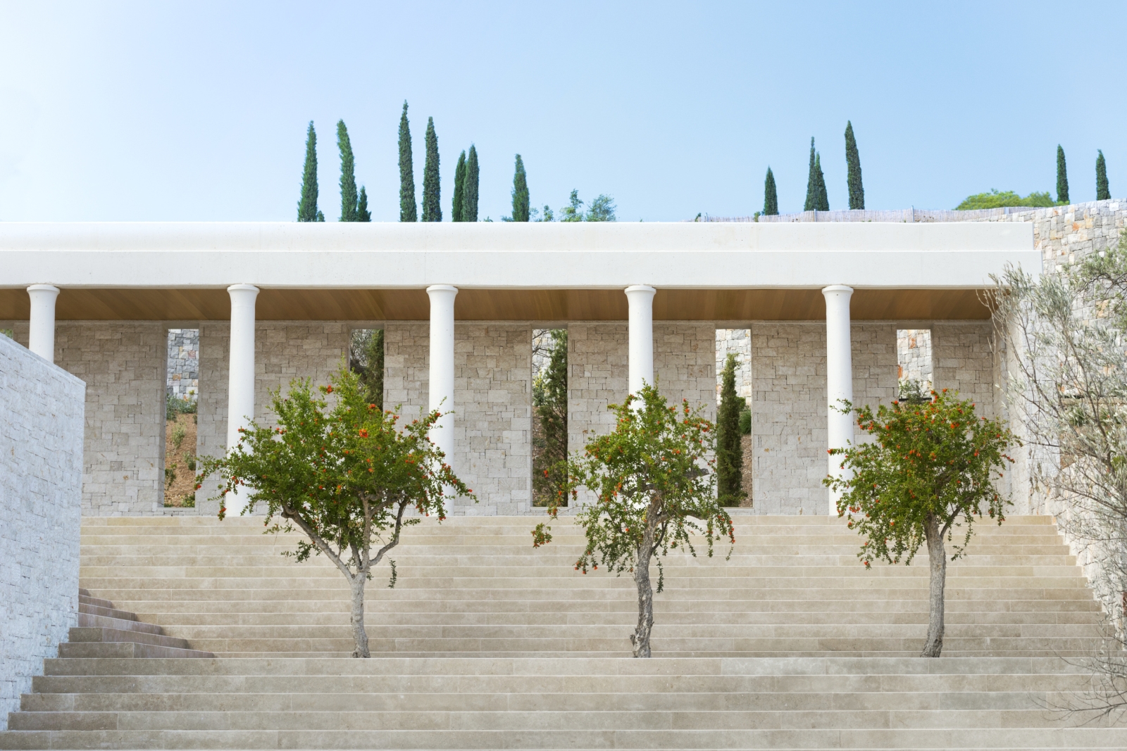 Three green trees in front of a white stair case