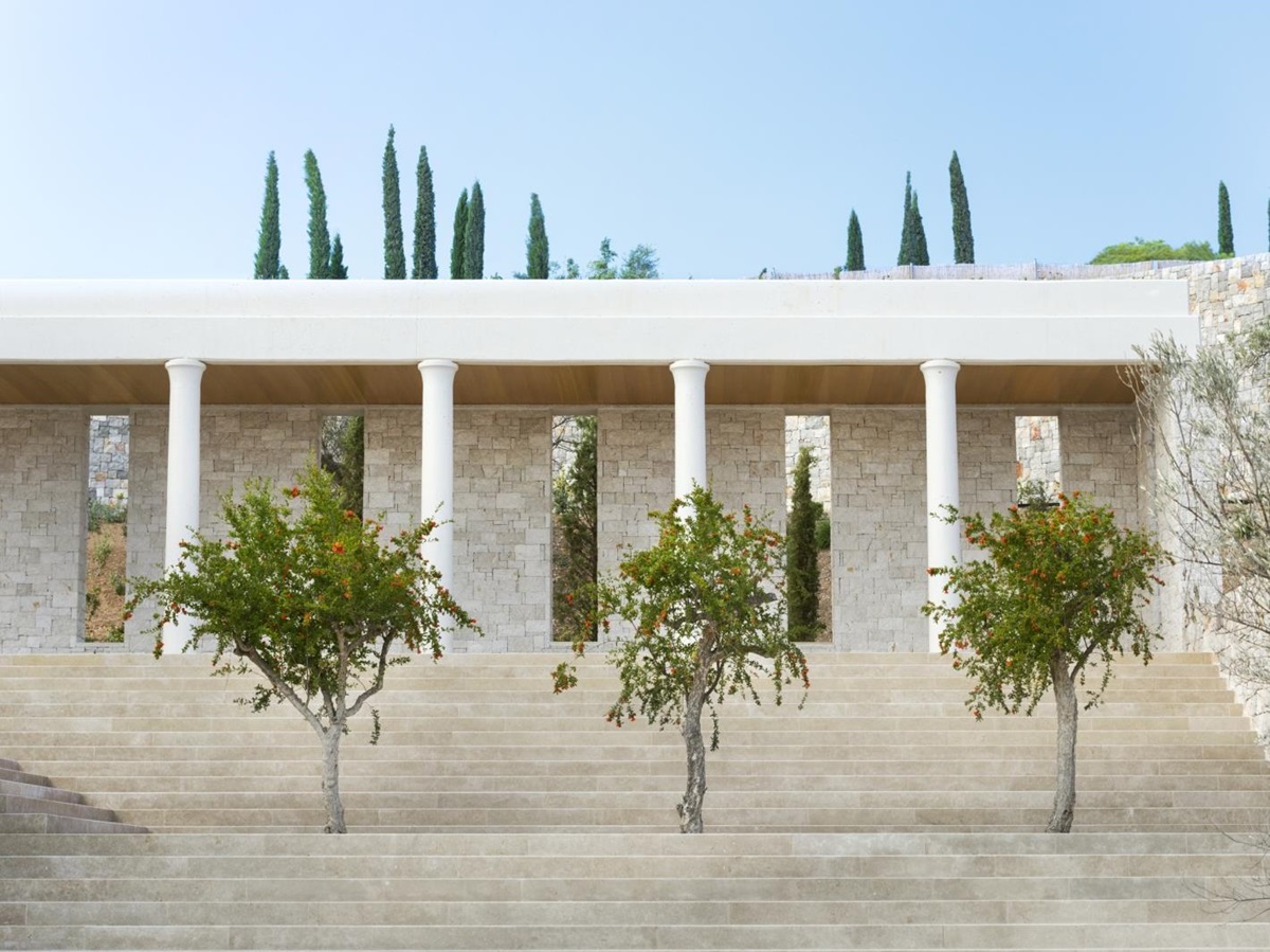 Three green trees in front of a white stair case