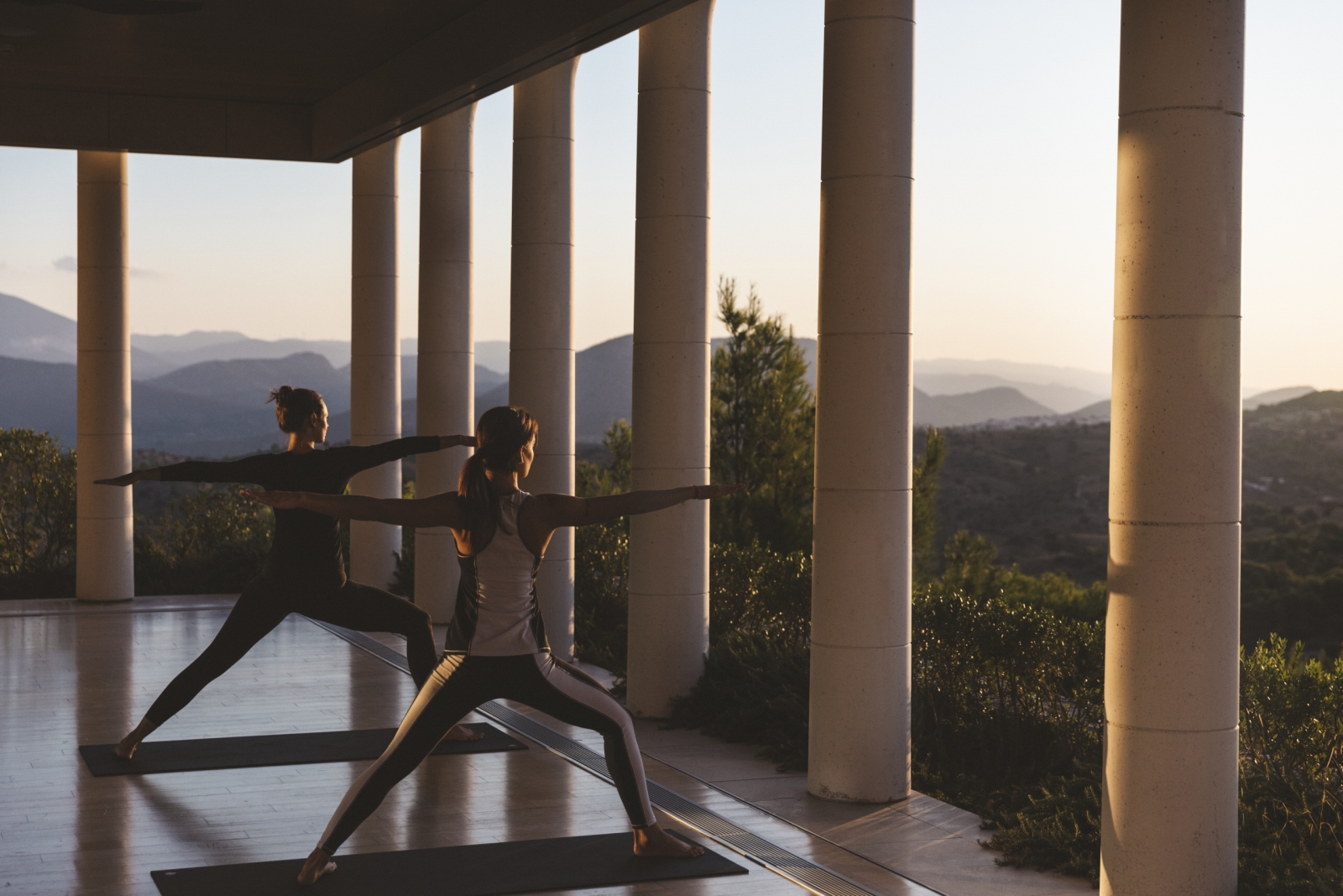 Two women in Warrior pose in the open-sided yoga studio