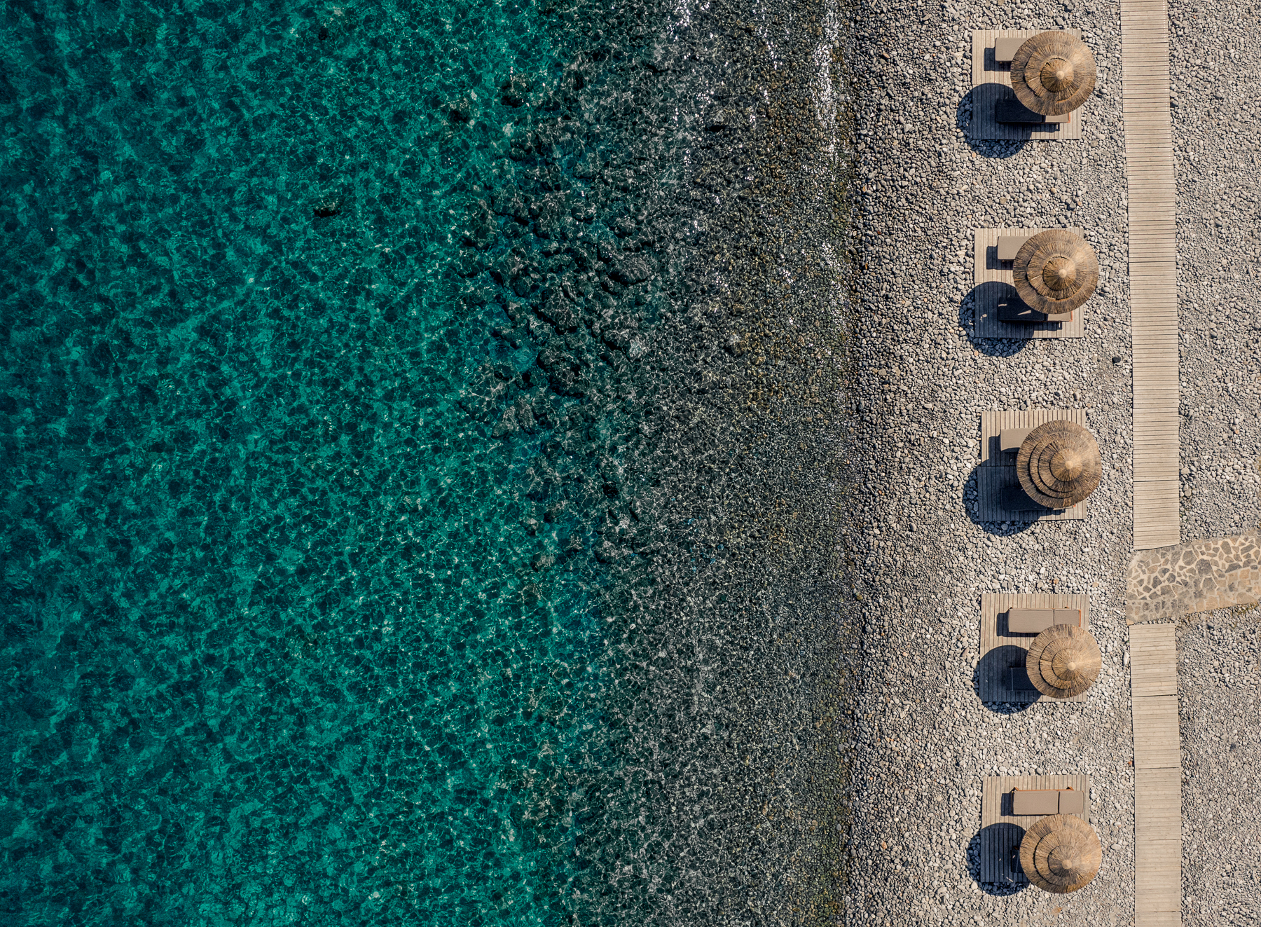 Aerial view of the pebble beach at Phāea Blue Palace in Crete