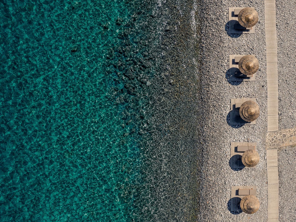 Aerial view of the pebble beach at Phāea Blue Palace in Crete