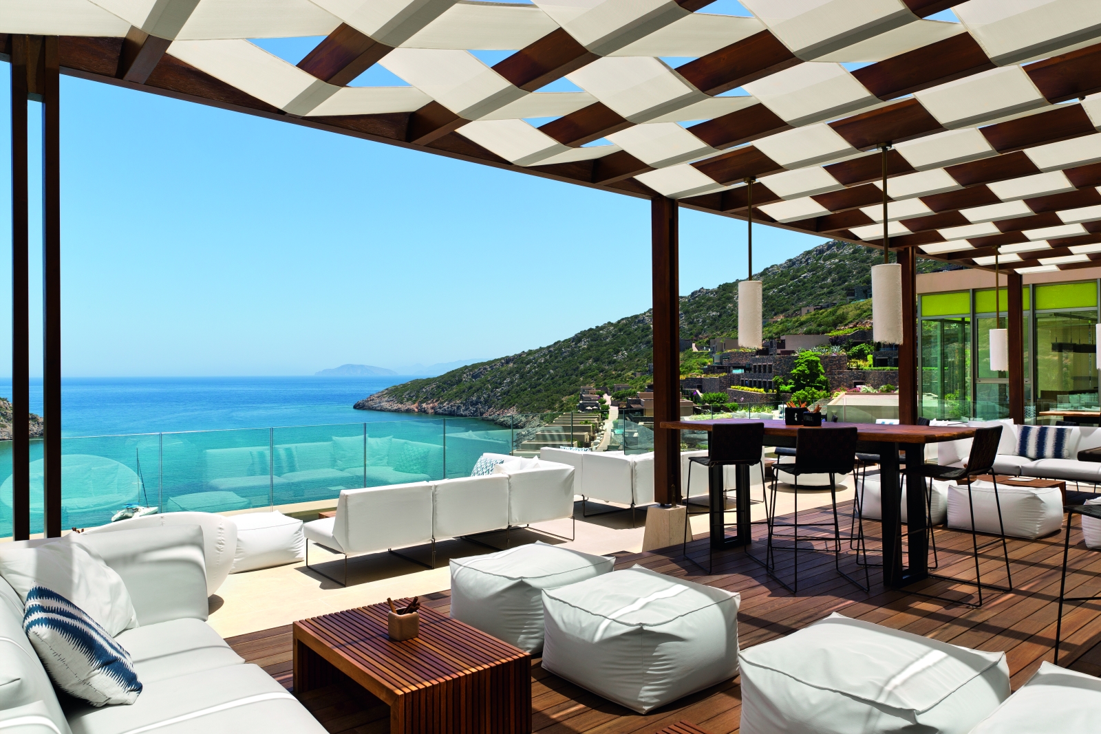 Comfortable sofas and chairs at Crystal Box Bar, overlooking the Mediterranean Sea and the bay, at luxury resort Daios Cove in Greece