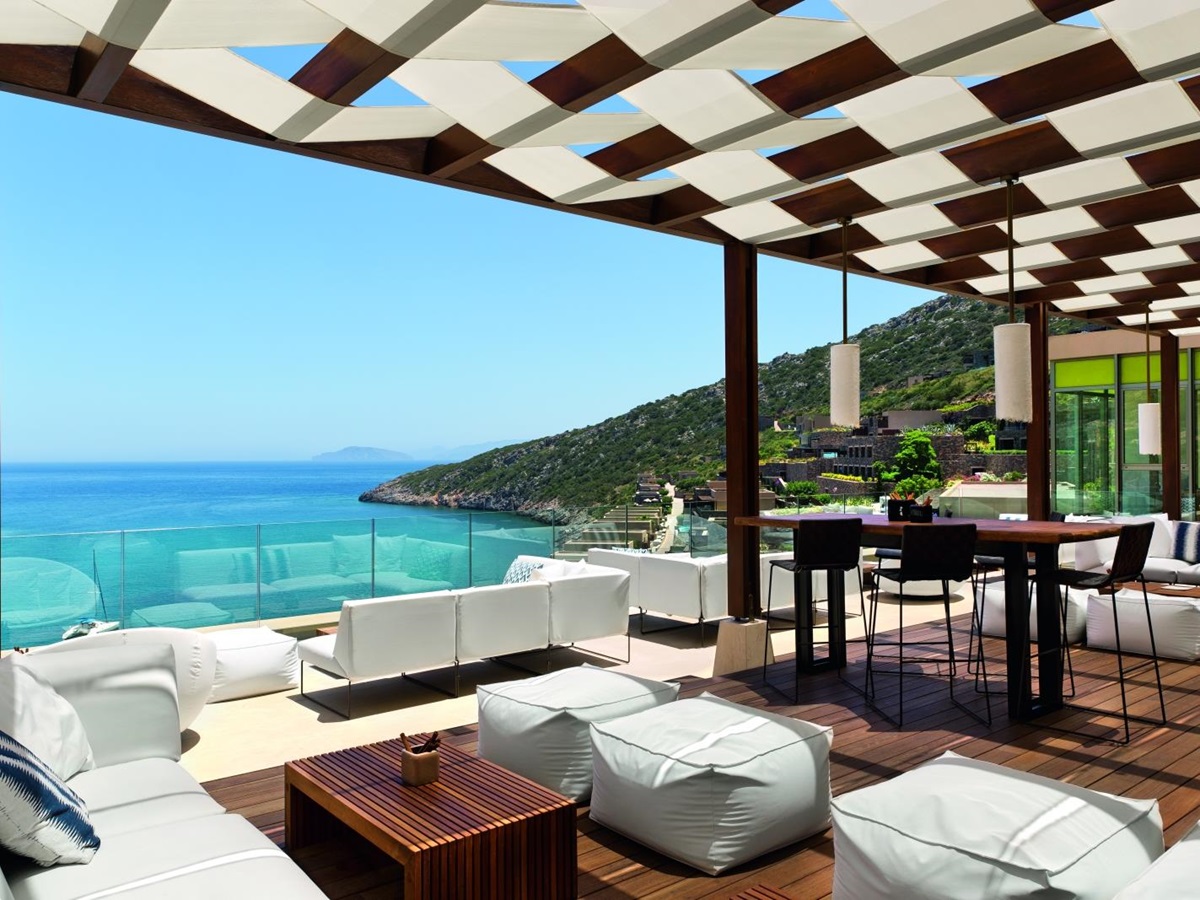 Comfortable sofas and chairs at Crystal Box Bar, overlooking the Mediterranean Sea and the bay, at luxury resort Daios Cove in Greece